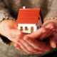 what you need to know about mortgages: woman's hands holding a model home