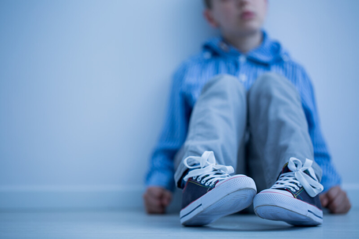 post-divorce anxiety in kids: anxious little boy sitting against a blue background