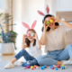 Mom and daughter holding easter eggs over there eyes and laughing