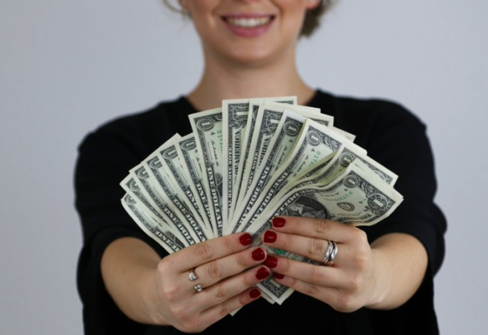 woman holding dollar bills fanned out in her hands